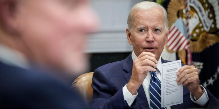 President Joe Biden, background, holds a cue card during a meeting with leaders on offshore wind energy on June 23, 2022