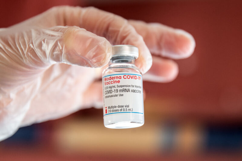 Extreme close up photo of a gloved hand holding a small jar.