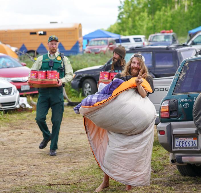 A Rainbow Family member shows a peace sign while a US Forest Service ranger helps transport supplies on June 26.  Rangers and Rainbows say they try to build relationships of mutual respect, and the Rainbows say they also respect the rangers' orders to enforce the rules.