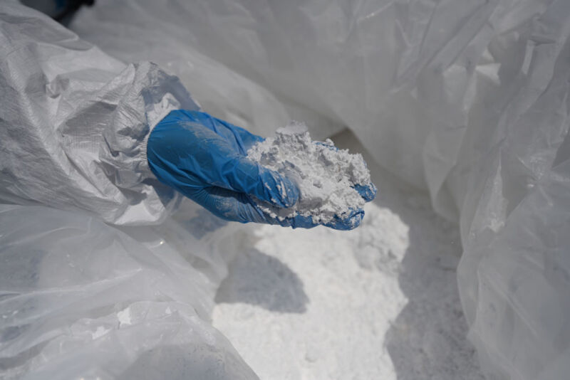 A customs officer inspects imported lithium carbonate at the Longwu Branch Terminal of Shanghai International Port Co., Ltd.