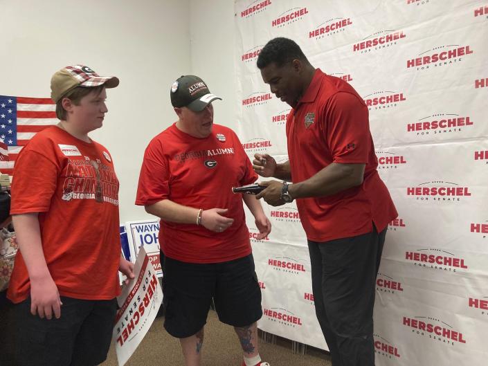 Herschel Walker, the Republican Senate candidate from Georgia, signs a soda bottle commemorating the 1980 football championship he won with the University of Georgia for Peter Bagarella, of Ellerslie, Georgia, after a speech at the Muscogee County GOP headquarters in Columbus, Georgia .