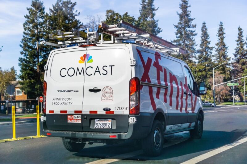 A Comcast Xfinity service van drives down a street.