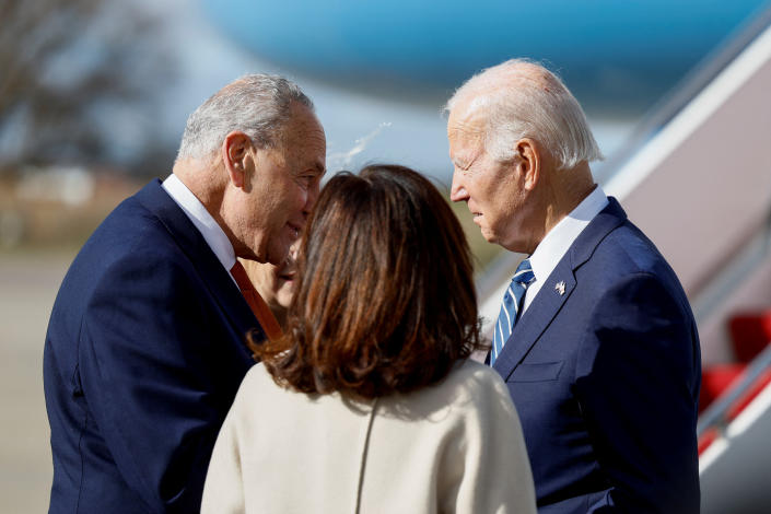 sen.  Chuck Schumer leans forward to tell President Biden something crucial, next to the Air Force One gangway.  Gov. Kathy Hochul has her back to the camera.