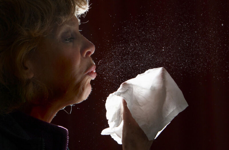 A close up image of a woman sneezing. 