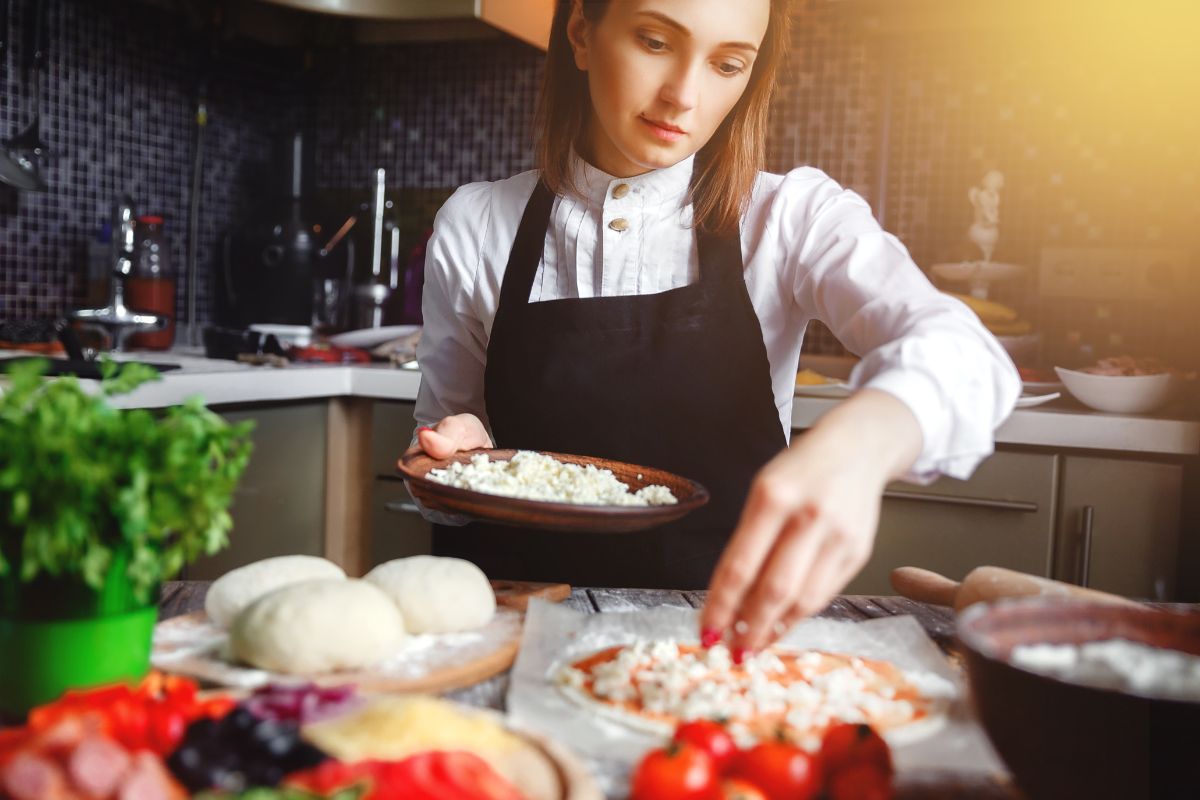 Chef in the kitchen prepares pizza