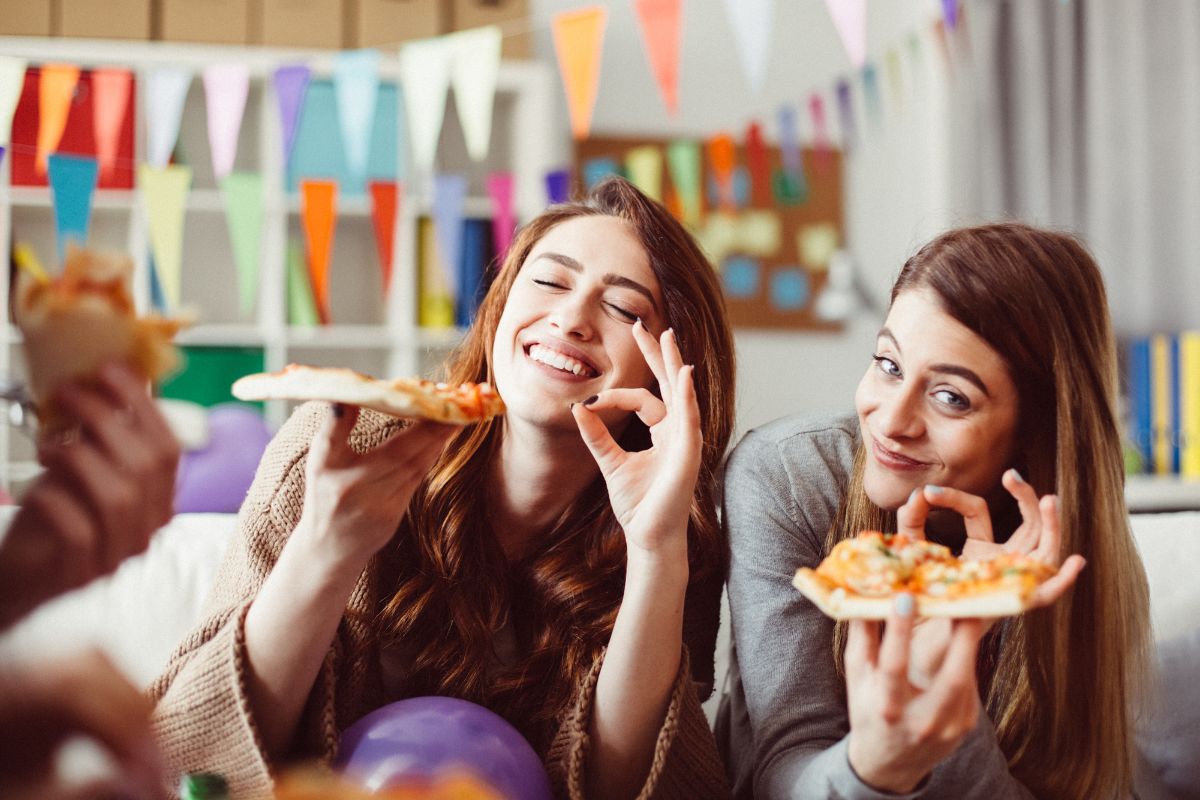 Women at a party eat pizza