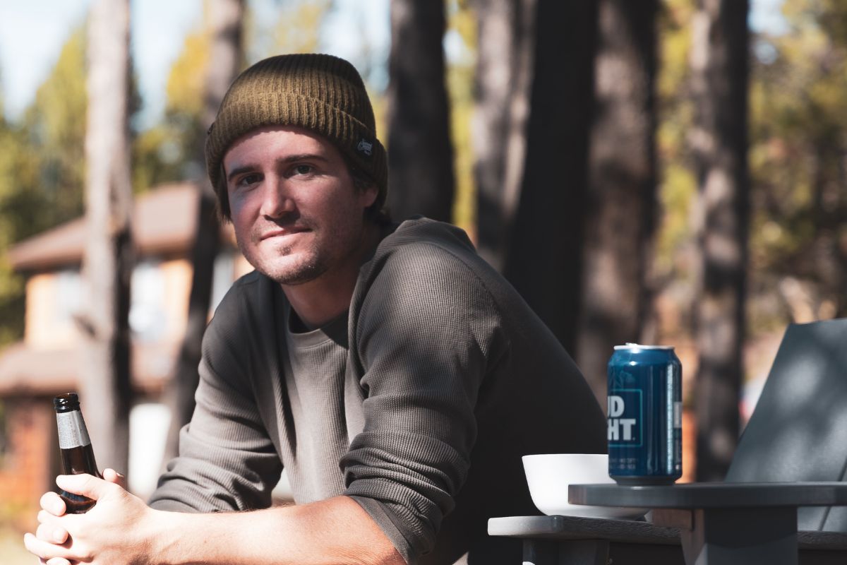 Man sitting with beer in hand and bud light on table