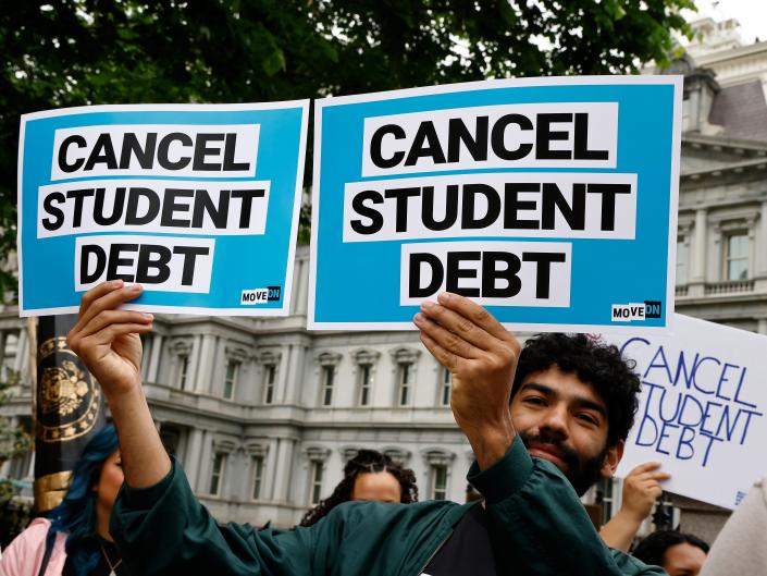 Man holds up two signs with the text "CANCEL STUDENT DEBT"