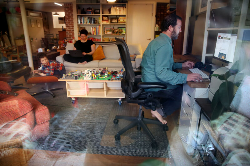 Parents work on their computers while their son is entertained at their Boston home in April 2020. 