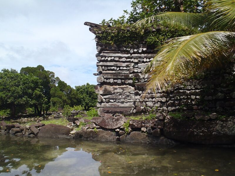 A building of dark stones above a water-filled canal.