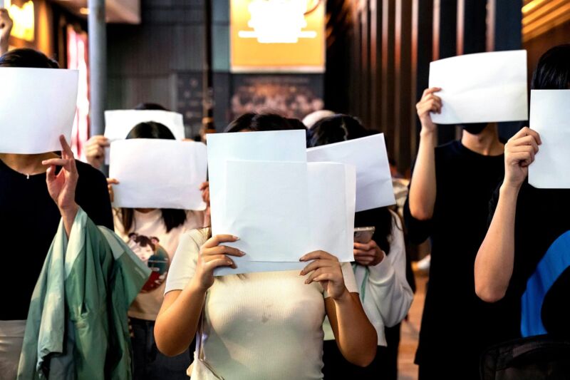 Protesters cover their faces with sheets of blank paper as they protest China's zero COVID policy in Hong Kong on November 28, 2022.