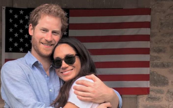 The Duke and Duchess of Sussex embrace in front of an American flag - Duke and Duchess of Sussex/Netflix