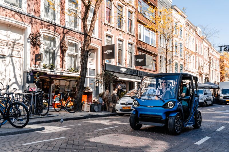A solar-powered city car drives through a Dutch city street