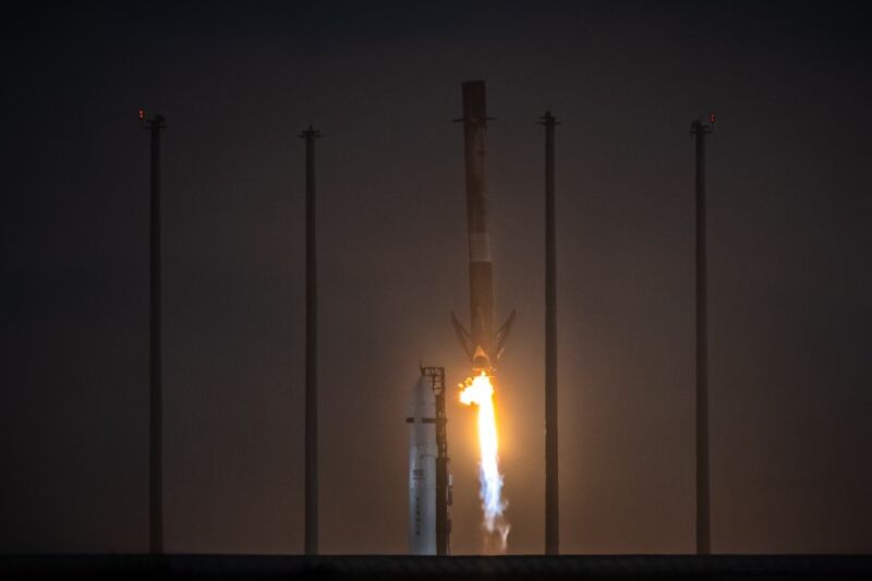 A Falcon 9 rocket lands Thursday evening after the launch of the OneWeb 1 mission.  Relativity Space's Terran 1 rocket sits in the background awaiting its debut launch.