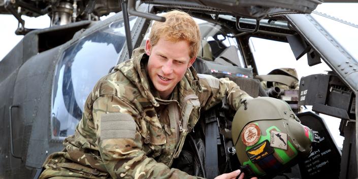 In this image released on Jan. 21, 2013, Prince Harry shows a television crew his cockpit helmet as he performs early morning checks while on an Apache helicopter on the British-controlled flight line at Camp Bastion on Dec. 12, 2012 in Afghanistan.