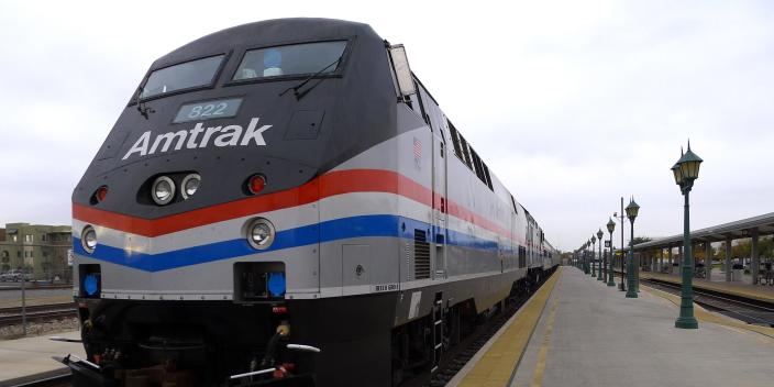 Grey, red and blue amtrak train on track at the station