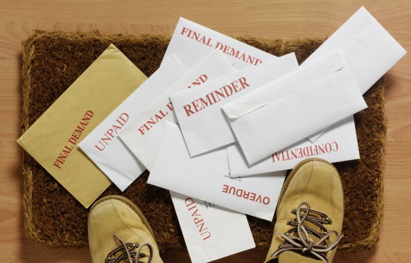 Envelopes with unpaid invoices on a doormat