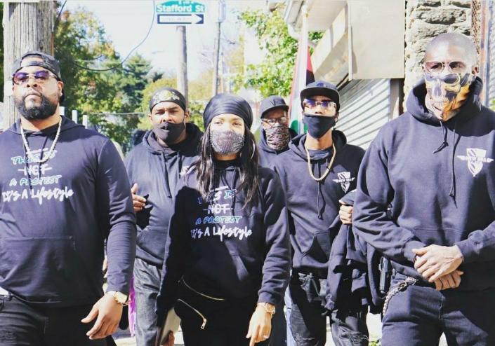 Six members of New Era Detroit, some wearing masks, walk the streets of Detroit, Michigan with founder Zeek Williams.