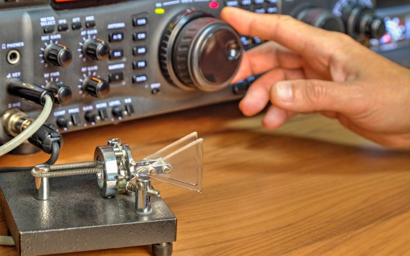 A hand adjusts a dial on a shortwave radio