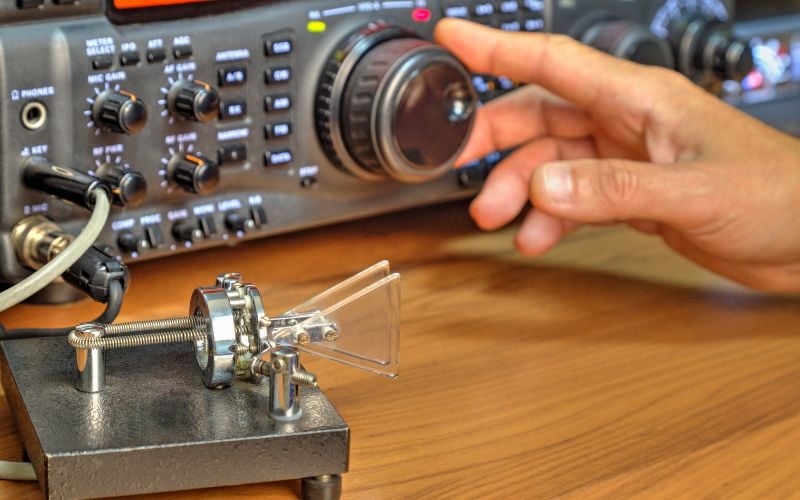 Hand tuning a metallic radio on a wooden table