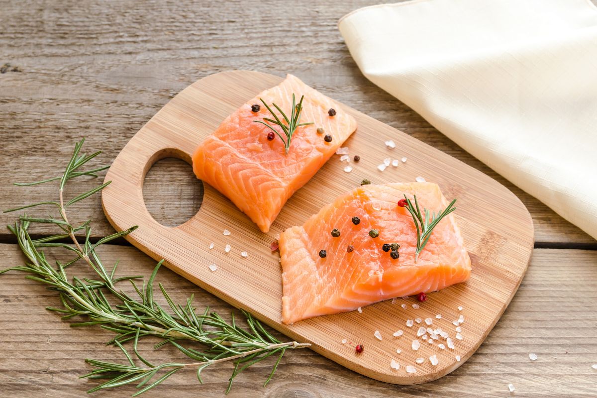 Raw salmon steaks with rosemary on wooden plate