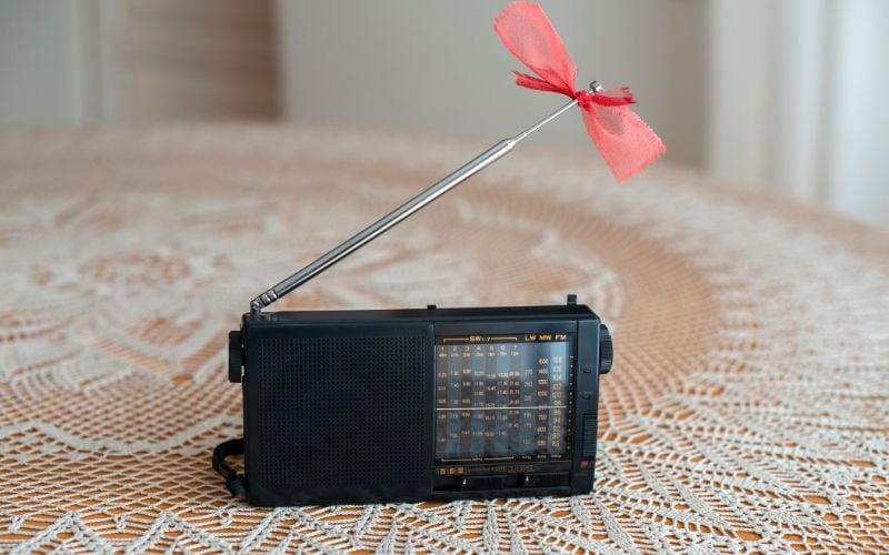 Black shortwave radio on a table with a red band around the antenna