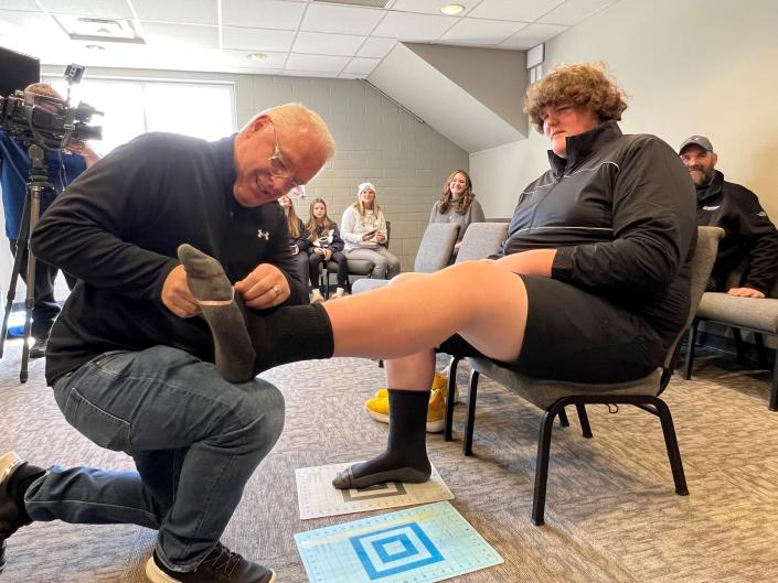 Robb Cropp, senior director of footwear development for Under Armor, measures Eric Kilburn Jr.'s feet.  at Bridgewood Church in Clarkston on March 26, 2023. Under Armor will make custom shoes for Eric's feet, which are estimated to be a size 23.