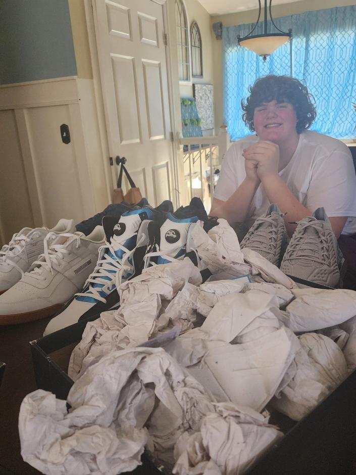 Goodrich's Eric Kilburn with a selection of size 22 Reebok shoes originally made for Shaquille O'Neal.  The 14 year old will be wearing these while waiting for bigger shoes to be custom made for him.