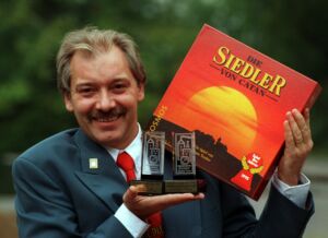 Klaus Teuber, with an early version of Catan and his Spiel des Jahres awards in 1995.