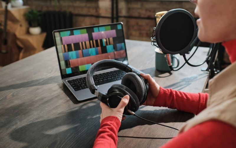 Radio presenter looking at his laptop with radio software and holding a pair of headphones