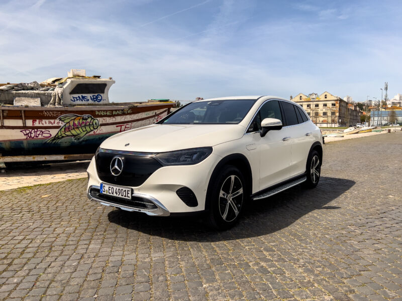 A white Mercedes EQE SUV next to a fishing boat