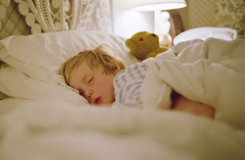 Young boy sleeps in a bed.