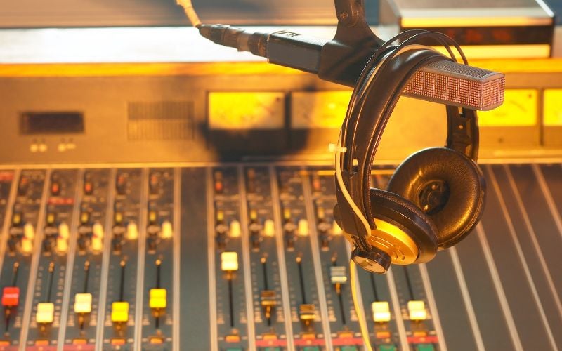 Headphones on a microphone and in the background a radio center with gold lighting 