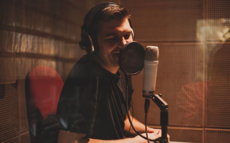 Man leaning into a microphone with headphones at a radio station in Canada 