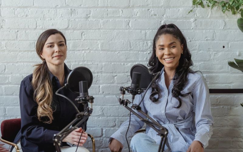 Two female radio presenters with microphones smiling 