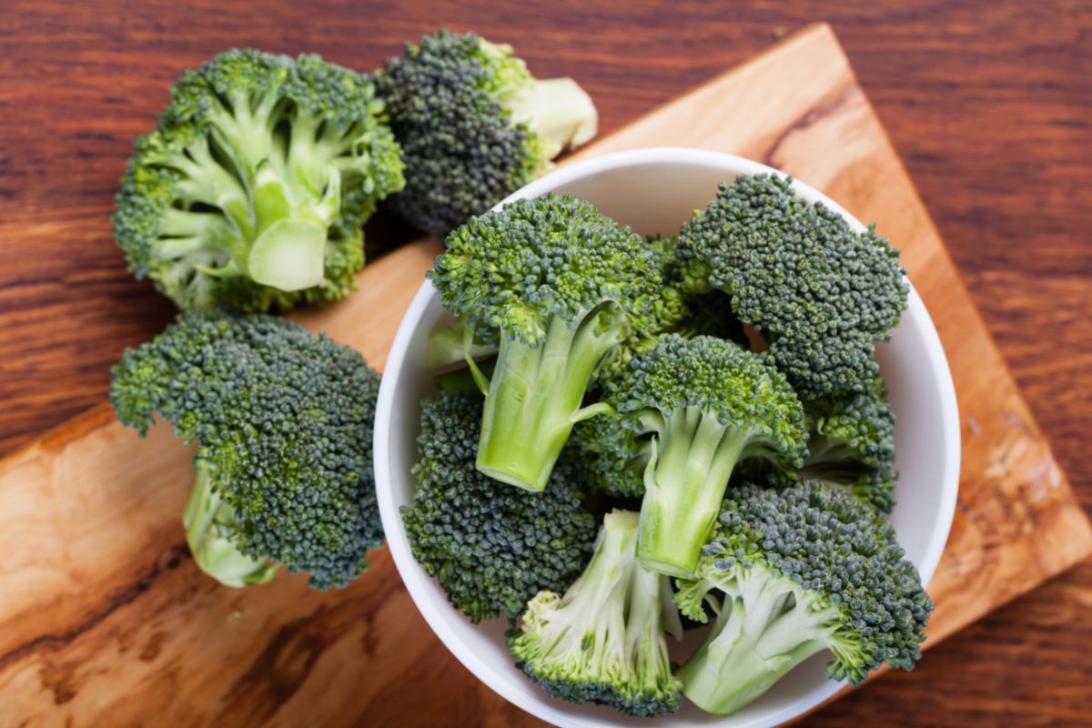 Broccoli in a bowl on a wooden cutting board