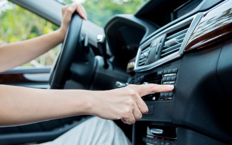 A person driving a car adjusts the radio settings in their vehicle