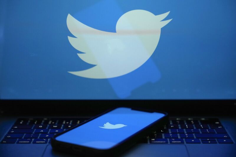 The Twitter logo can be seen on a laptop screen and a smartphone screen.