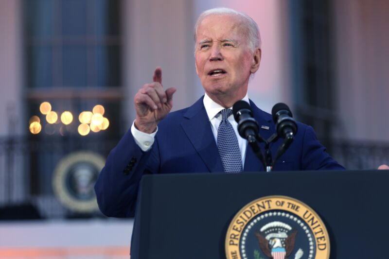 President Joe Biden points with his right hand and speaks into microphones on a podium outside the White House.