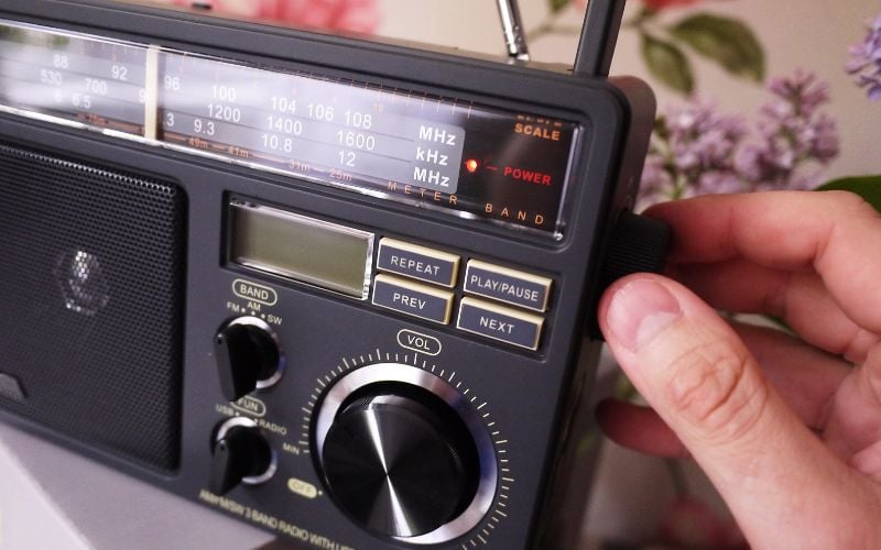 Hand-operated radio in front of a room with floral wallpaper