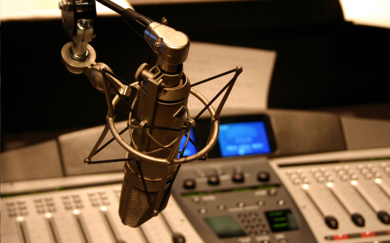 Microphone over control panel in a dark radio studio
