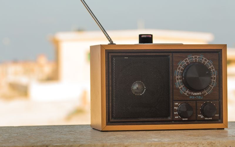 Small brown radio playing sports radio station outside on record on a clear day