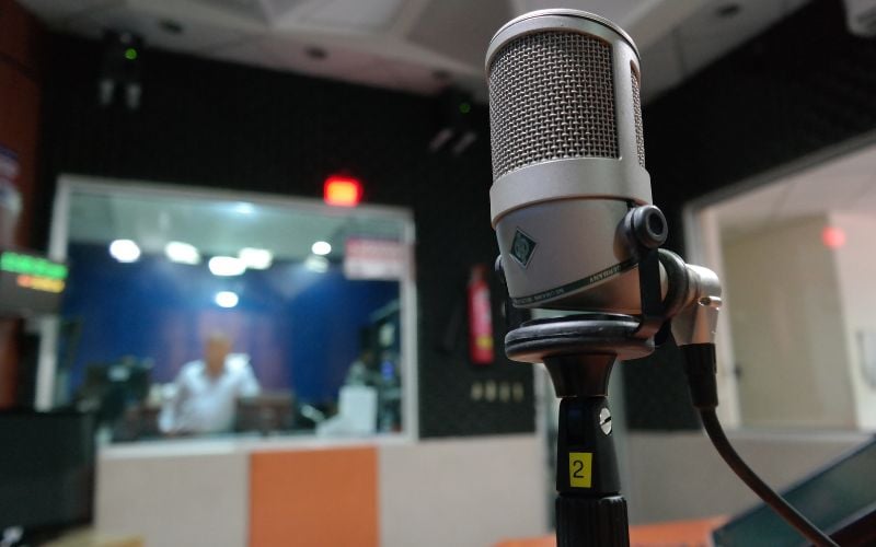 Radio studio microphone against a blurred background of people in a radio studio broadcasting on LBC