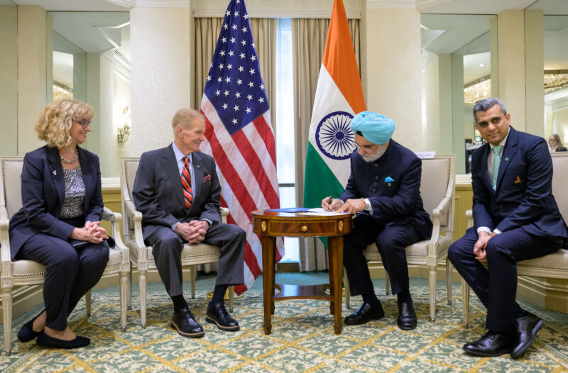 Taranjit Sandhu, India's ambassador to the United States, signs the Artemis Accords in Washington on June 21.  NASA Administrator Bill Nelson watches from across the table.