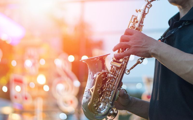 Man on stage playing saxophone with bright colorful lights in background