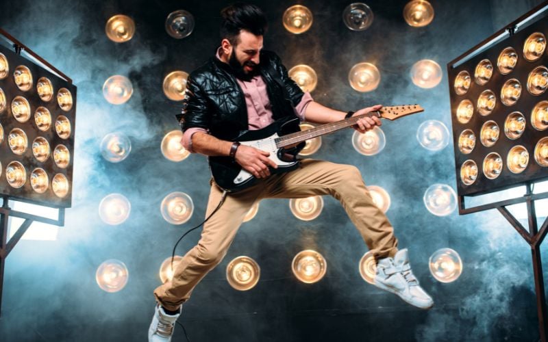 Pop star plays guitar against smoke and bright stage lights on UK radio