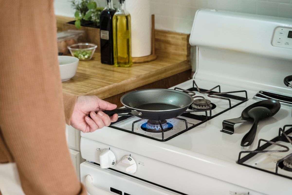 Person Heating a Frying Pan on a Stove Top